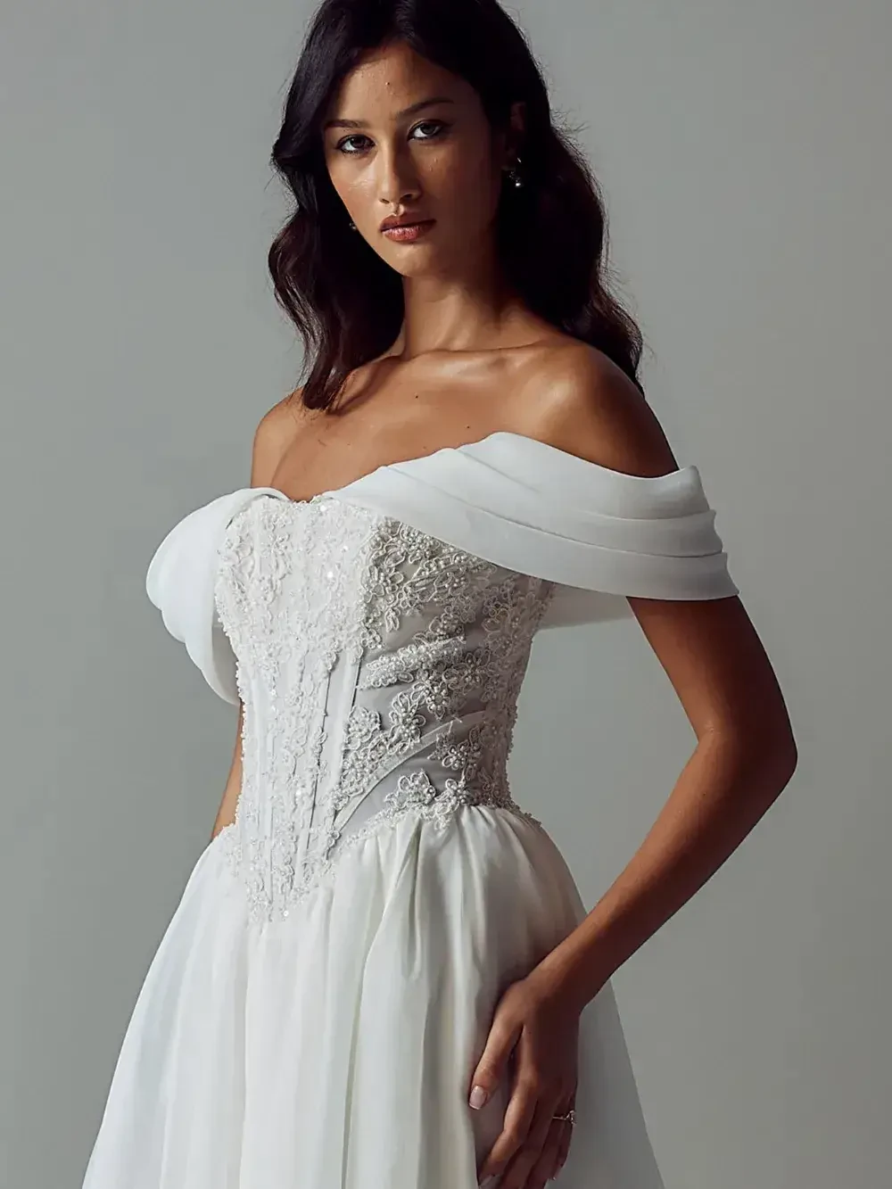 A woman in a white off-the-shoulder dress with intricate lace details.