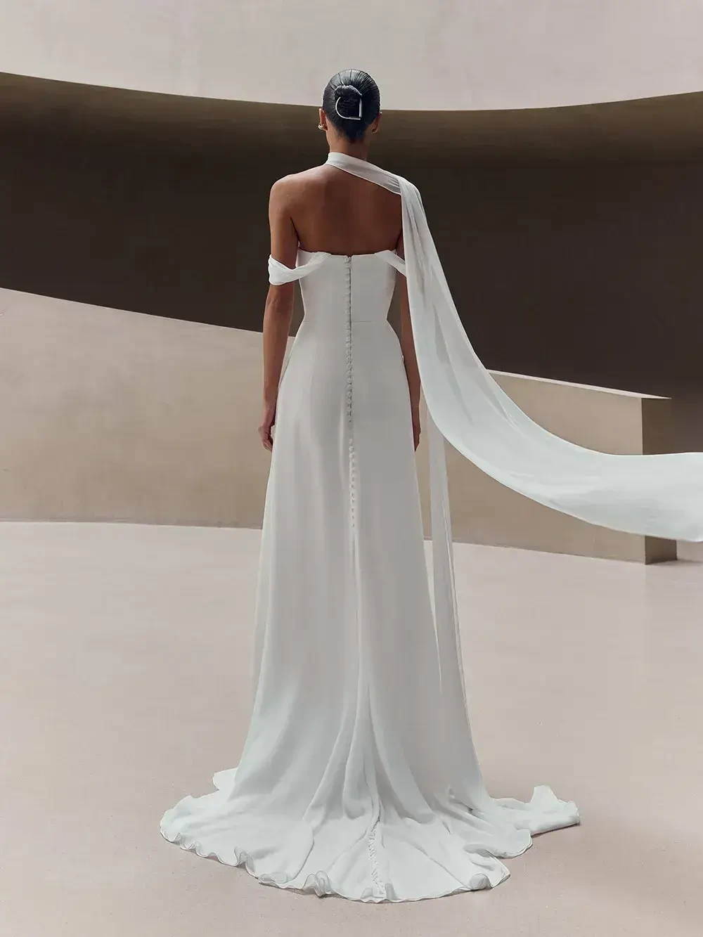 model is wearing an open back off the shoulder bridal gown