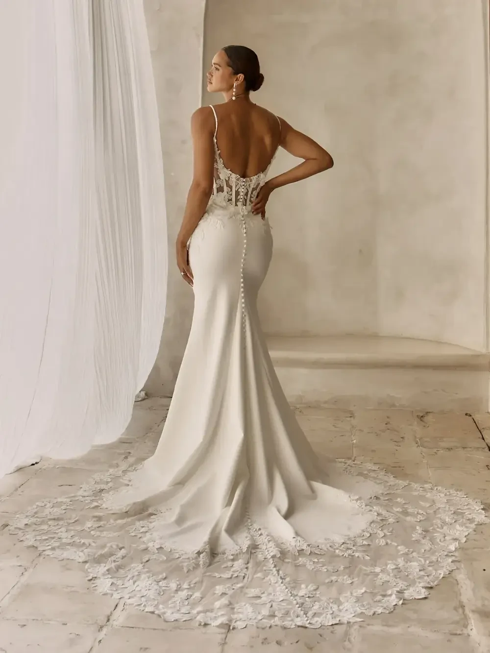model is wearing an open back sleeveless lace wedding dress