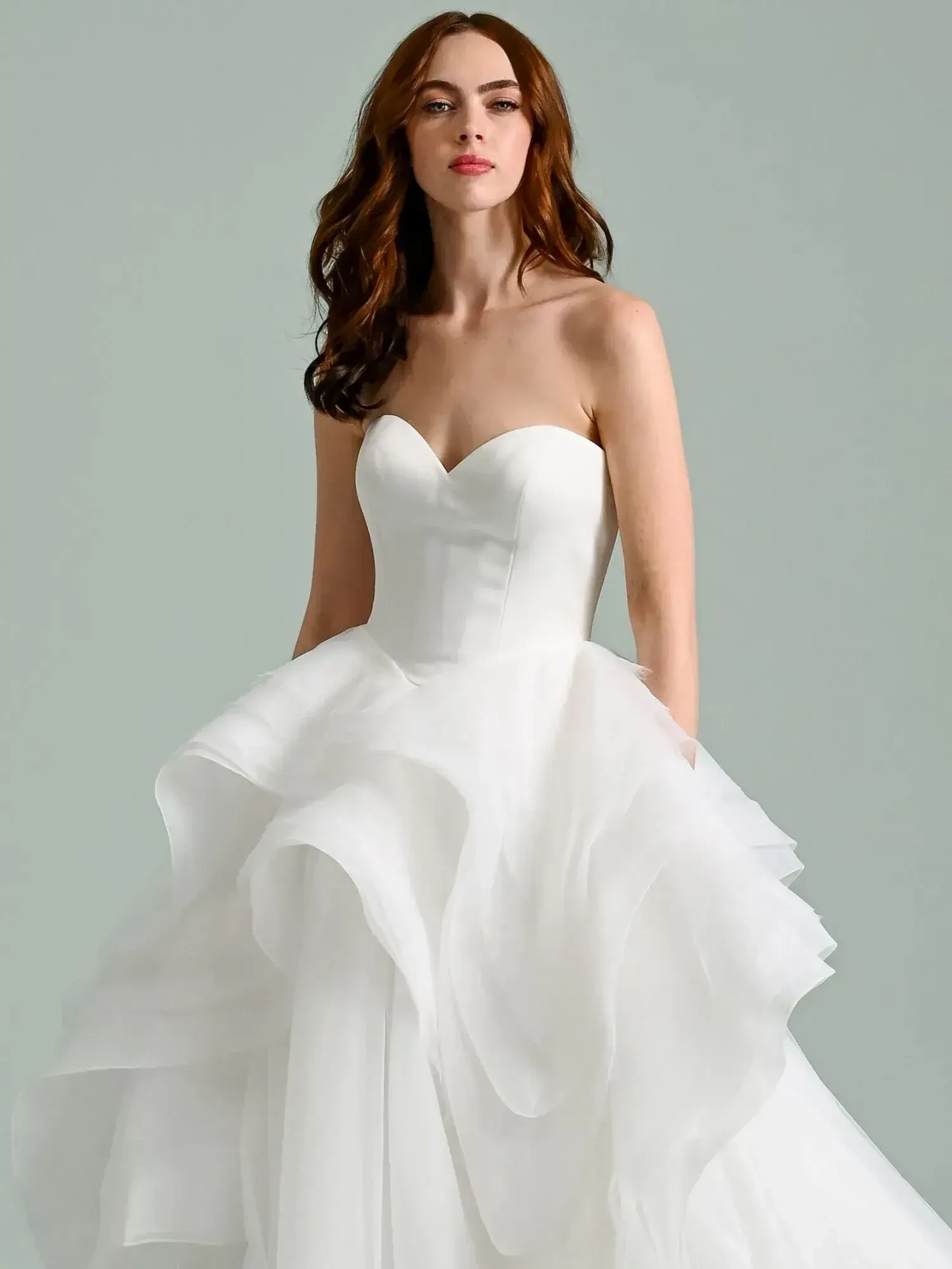A woman in a strapless white wedding dress with a ruffled skirt.